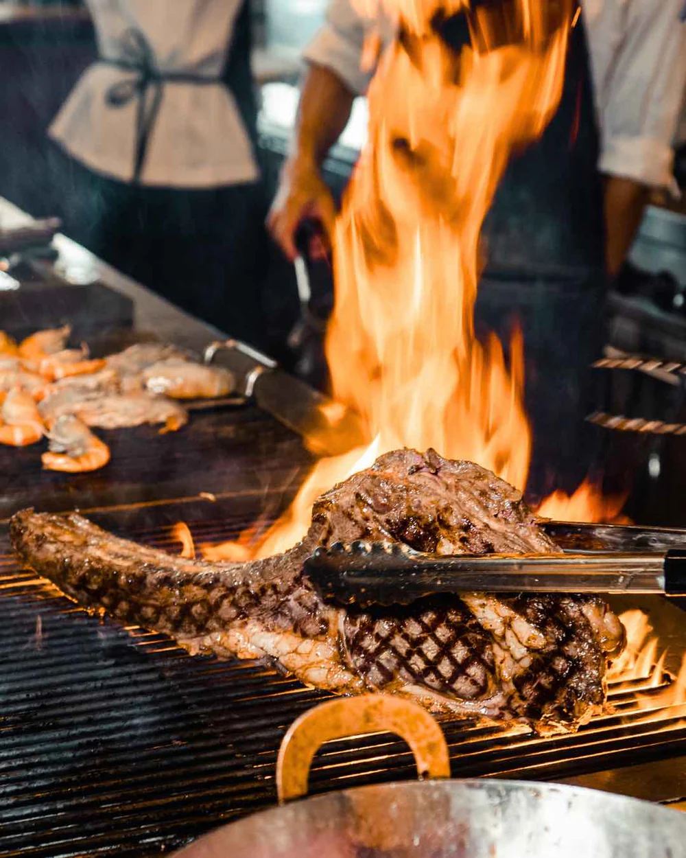 Steakhouse chef grilling a Black Angus tomahawk over open flame